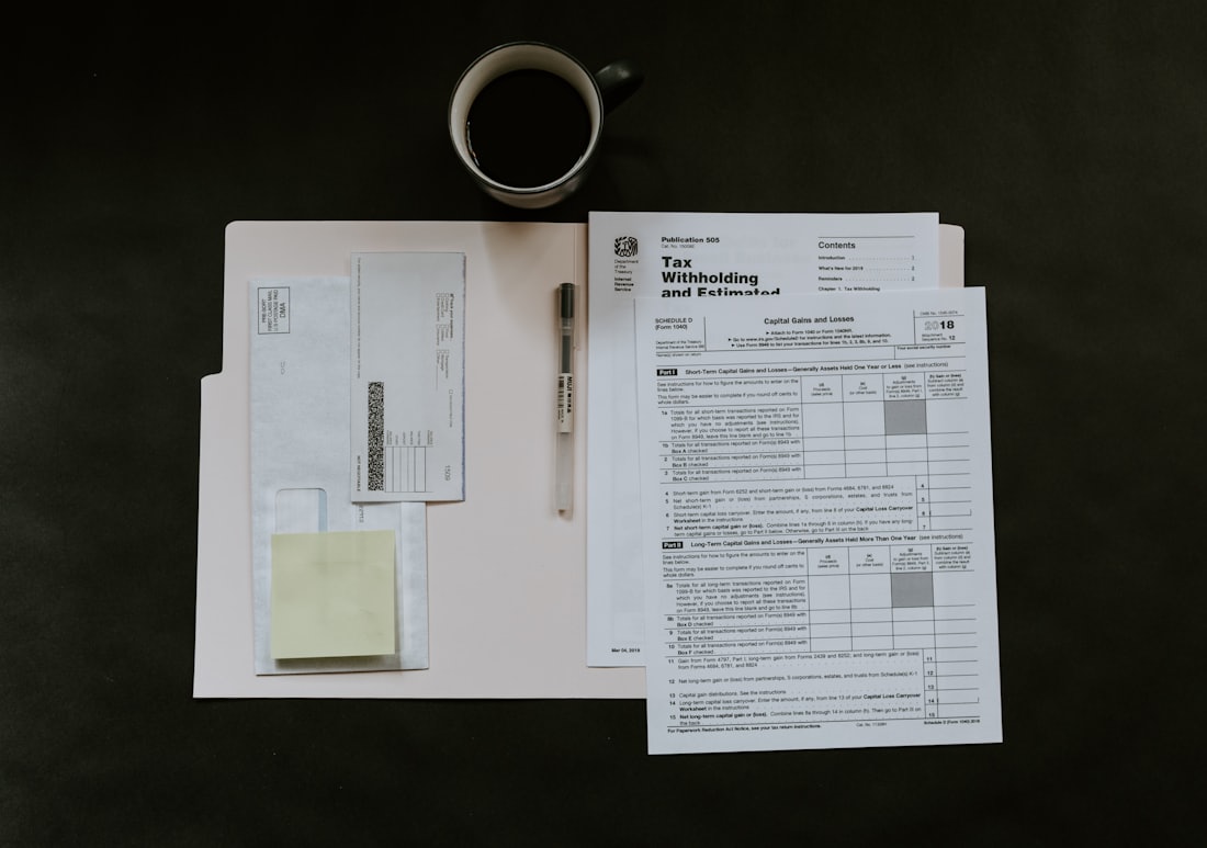 Documentos oficiales, un bolígrafo y una taza de café sobre un escritorio oscuro
